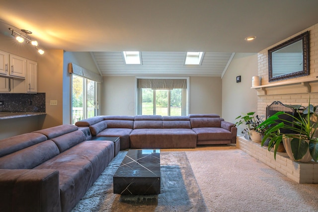 living room with a healthy amount of sunlight, lofted ceiling, and a brick fireplace