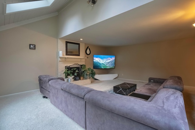 carpeted living room with a brick fireplace and vaulted ceiling with skylight