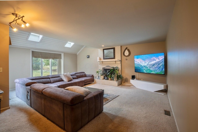 carpeted living room with vaulted ceiling with skylight and a fireplace