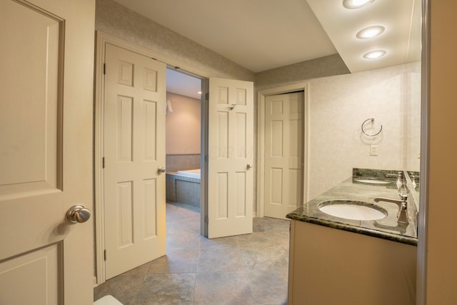 bathroom with vanity and tiled tub