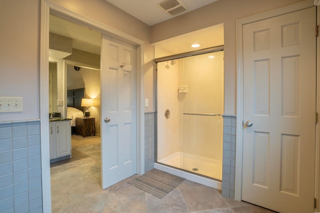 bathroom with tile patterned flooring, tile walls, and a shower with shower door