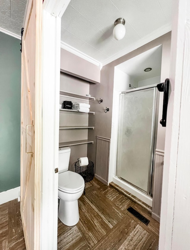 bathroom featuring ornamental molding, toilet, a shower with shower door, and hardwood / wood-style floors