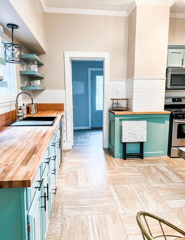 kitchen featuring pendant lighting, sink, appliances with stainless steel finishes, green cabinetry, and wood counters