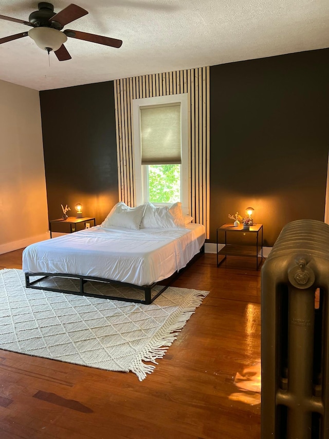 bedroom featuring ceiling fan, hardwood / wood-style flooring, and a textured ceiling