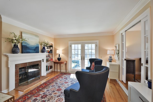 living room with crown molding, a fireplace, french doors, and light wood-type flooring