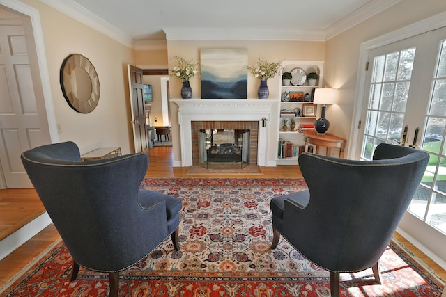 living room featuring crown molding, built in features, a fireplace, and light hardwood / wood-style flooring