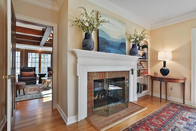 living room with hardwood / wood-style floors, ornamental molding, and a brick fireplace