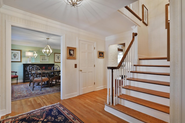 entryway with an inviting chandelier, hardwood / wood-style floors, and crown molding