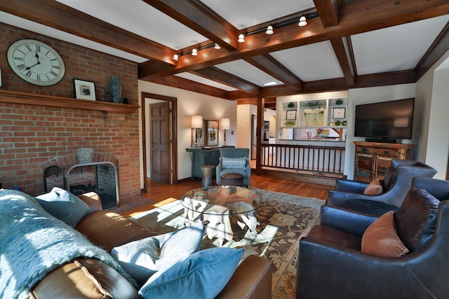 living room with hardwood / wood-style flooring, a fireplace, beamed ceiling, and brick wall