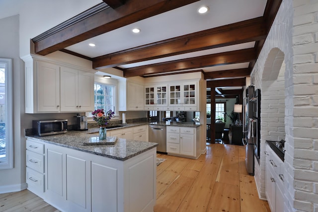 kitchen featuring light wood-type flooring, kitchen peninsula, white cabinets, and appliances with stainless steel finishes