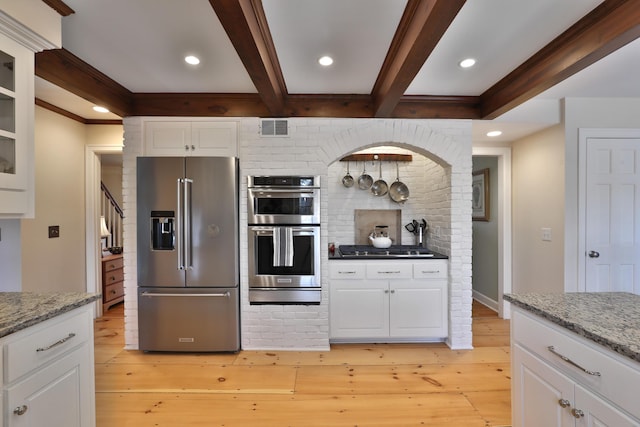 kitchen with white cabinetry, appliances with stainless steel finishes, beamed ceiling, light stone countertops, and light hardwood / wood-style floors