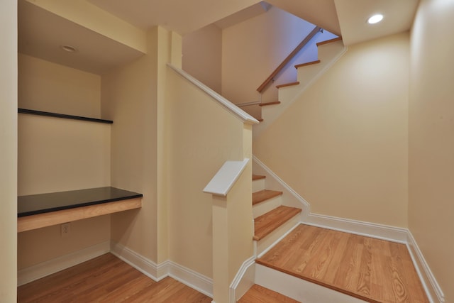 stairs with wood-type flooring and built in desk