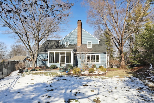 snow covered rear of property featuring a patio area and a sunroom