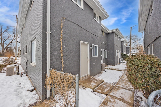 snow covered property with central AC unit