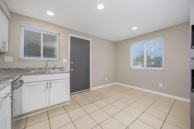 kitchen with light tile patterned floors, dishwasher, sink, and white cabinets