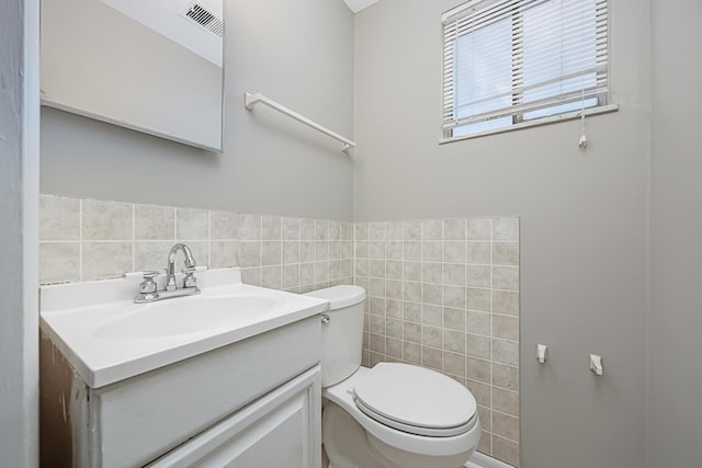 bathroom featuring vanity, tile walls, and toilet