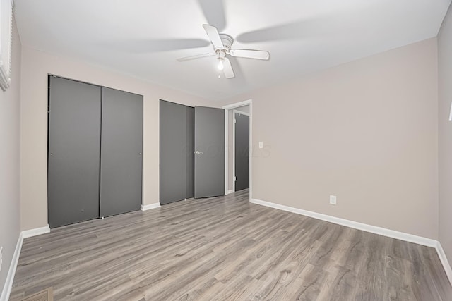 unfurnished bedroom with ceiling fan, light hardwood / wood-style floors, and two closets