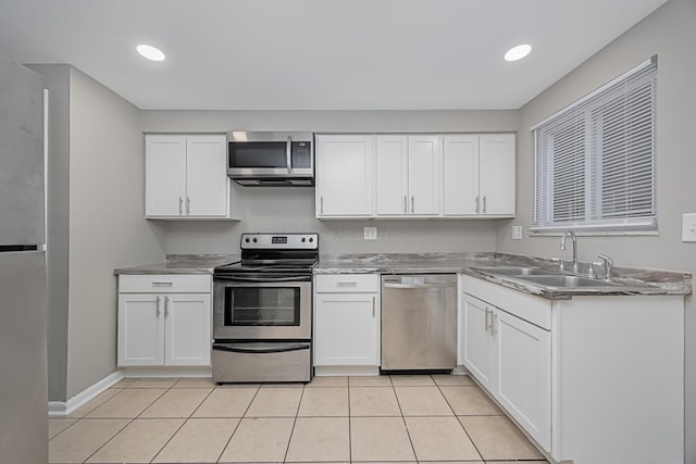 kitchen with light tile patterned flooring, appliances with stainless steel finishes, sink, and white cabinets