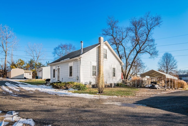 view of side of home featuring a carport, an outbuilding, and central AC unit