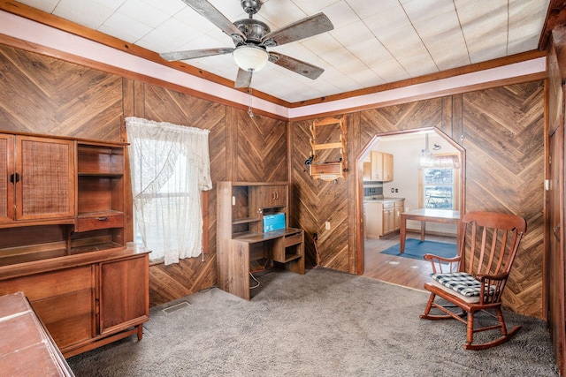 office space featuring wooden walls, ceiling fan, and carpet flooring