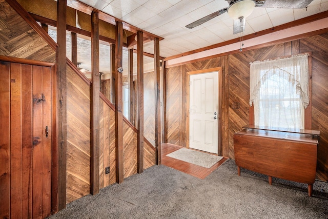 miscellaneous room featuring ceiling fan, wooden walls, and carpet floors