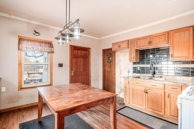 kitchen with sink, gas range gas stove, crown molding, hanging light fixtures, and light hardwood / wood-style flooring