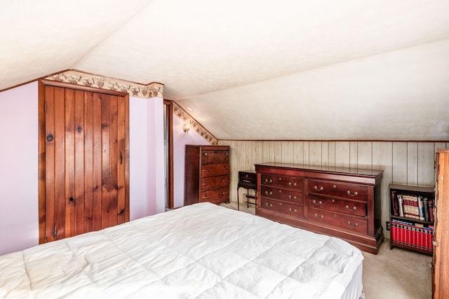 bedroom with lofted ceiling, light colored carpet, and wood walls