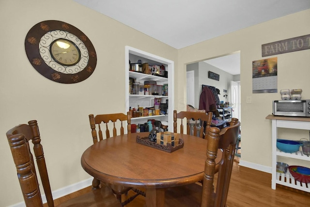 dining space with hardwood / wood-style floors and built in features