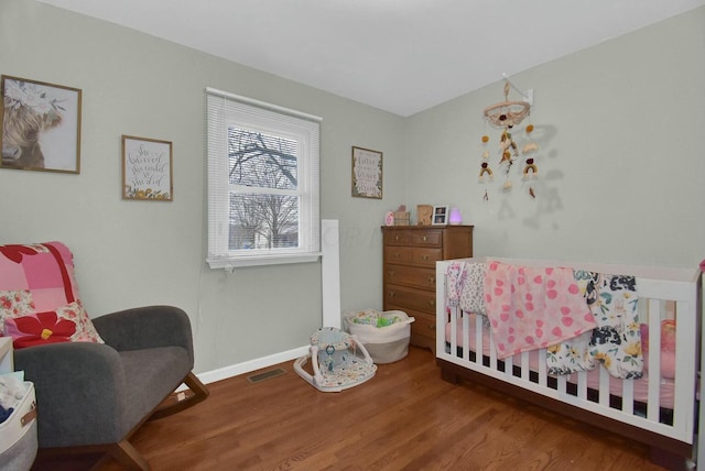 bedroom with a nursery area and hardwood / wood-style floors