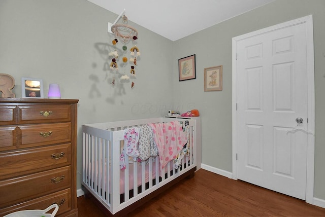 bedroom with a nursery area and dark hardwood / wood-style floors