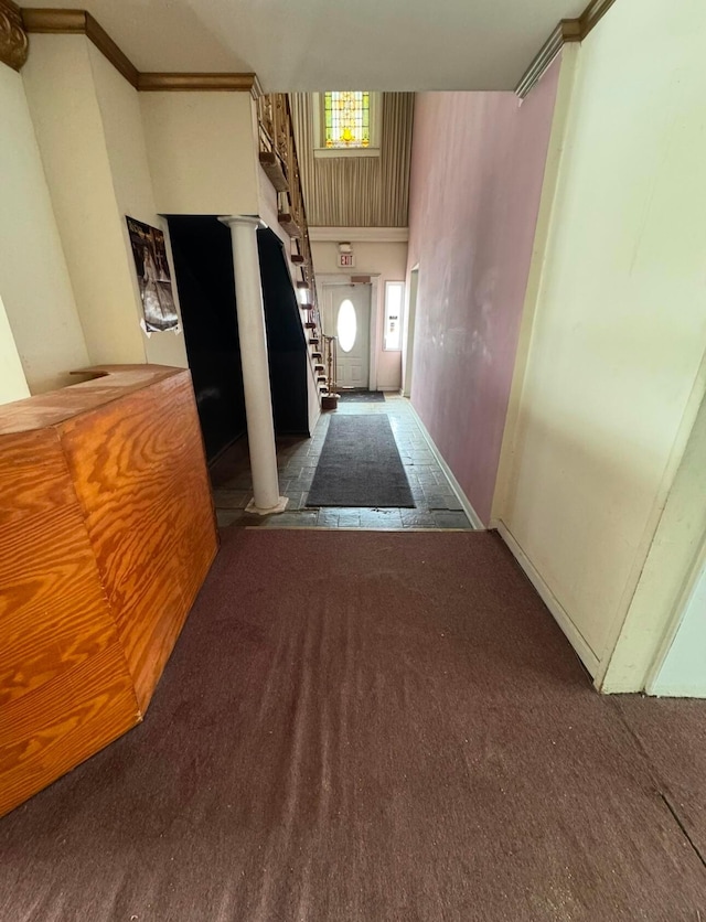 hallway featuring crown molding, dark carpet, and ornate columns