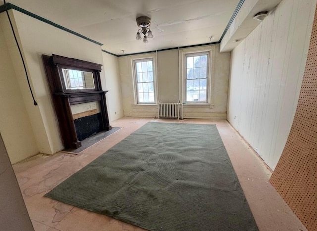 unfurnished living room with radiator heating unit and wood walls