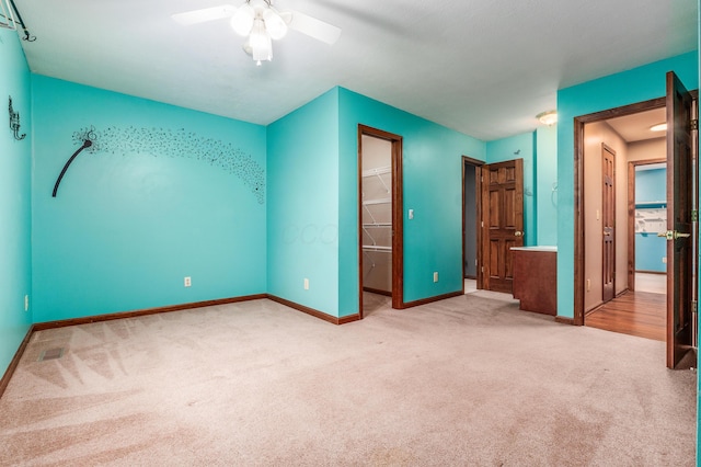 unfurnished bedroom with ceiling fan, a spacious closet, a closet, and carpet