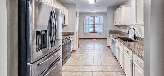 kitchen featuring tasteful backsplash, dark stone counters, stainless steel appliances, and sink