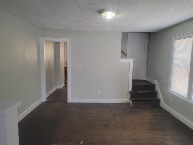 unfurnished living room featuring dark wood-type flooring and a textured ceiling