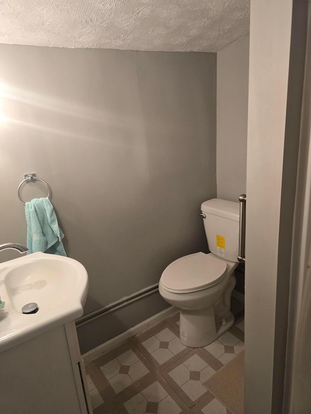 bathroom featuring vanity, a textured ceiling, and toilet