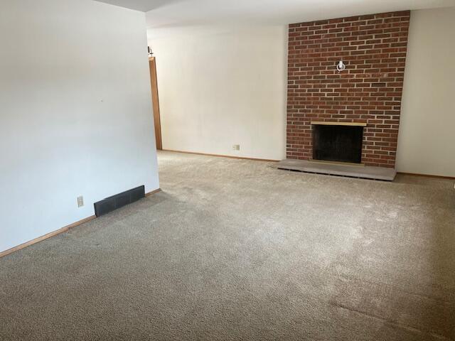 unfurnished living room with carpet and a brick fireplace