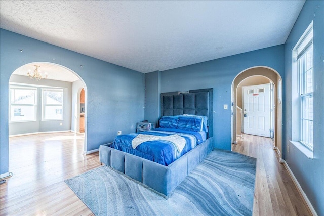 bedroom with a chandelier, a textured ceiling, and light hardwood / wood-style flooring