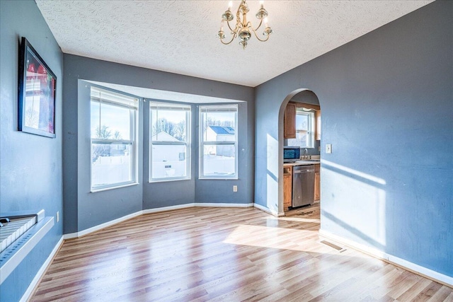 spare room with a notable chandelier, sink, a textured ceiling, and light wood-type flooring