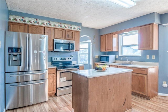 kitchen featuring sink, a center island, a textured ceiling, and appliances with stainless steel finishes