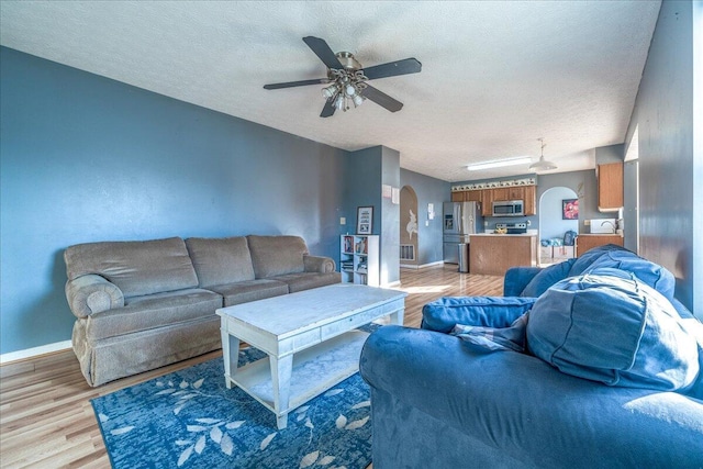 living room featuring ceiling fan, a textured ceiling, and light hardwood / wood-style flooring