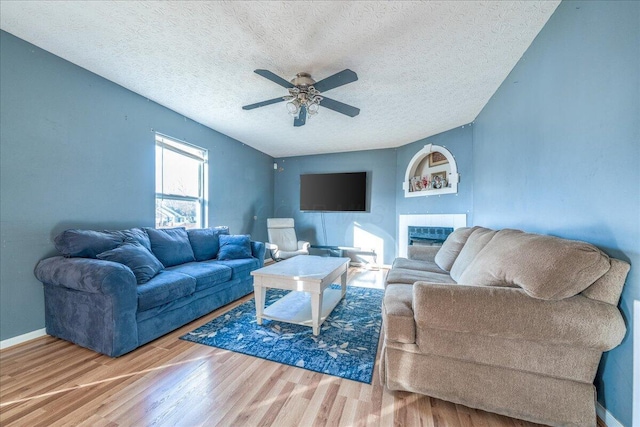 living room with ceiling fan, wood-type flooring, and a textured ceiling