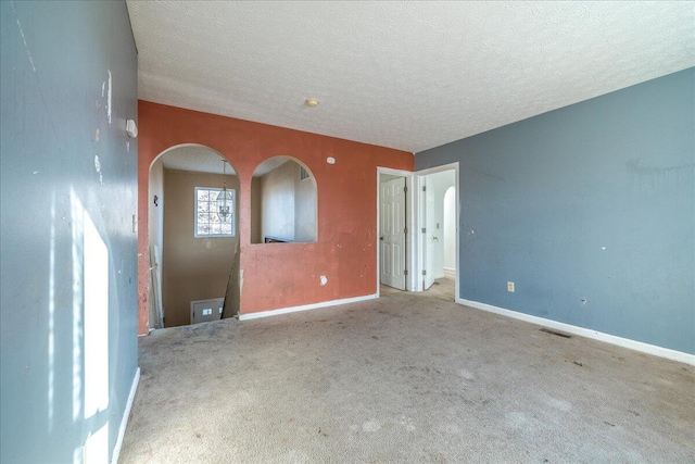 carpeted empty room featuring a textured ceiling