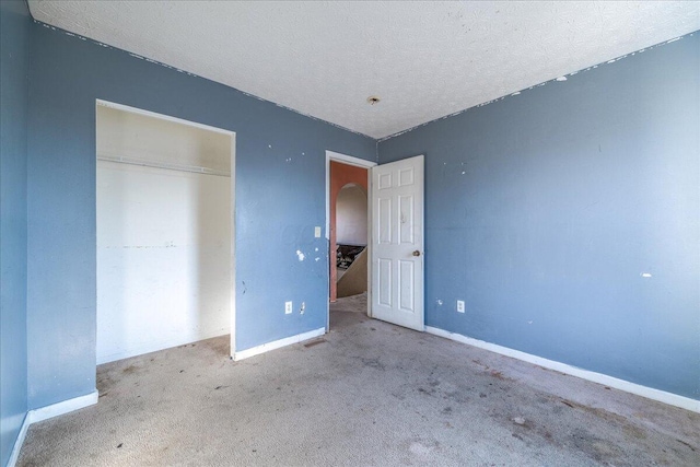 unfurnished bedroom featuring a closet, a textured ceiling, and carpet