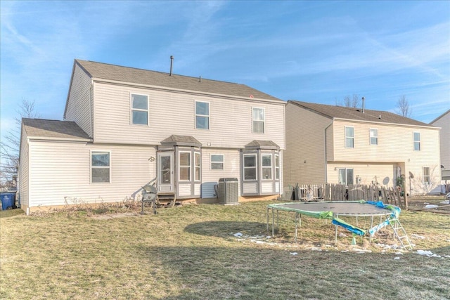 back of property with a trampoline, cooling unit, and a lawn