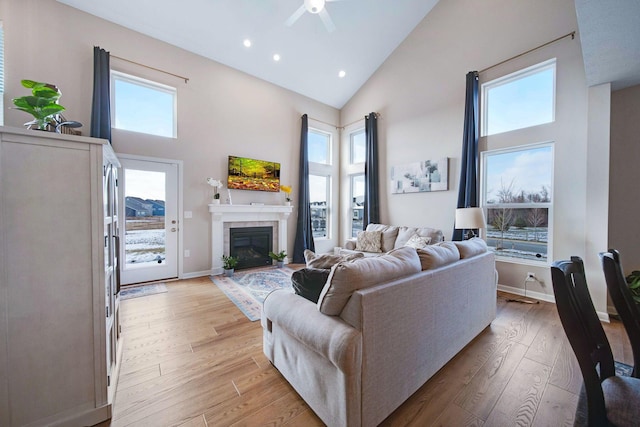 living room featuring a fireplace, high vaulted ceiling, and light wood-type flooring