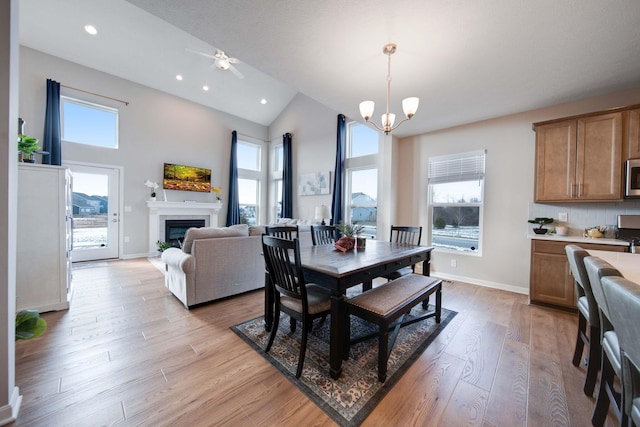 dining room with an inviting chandelier, light hardwood / wood-style flooring, and high vaulted ceiling