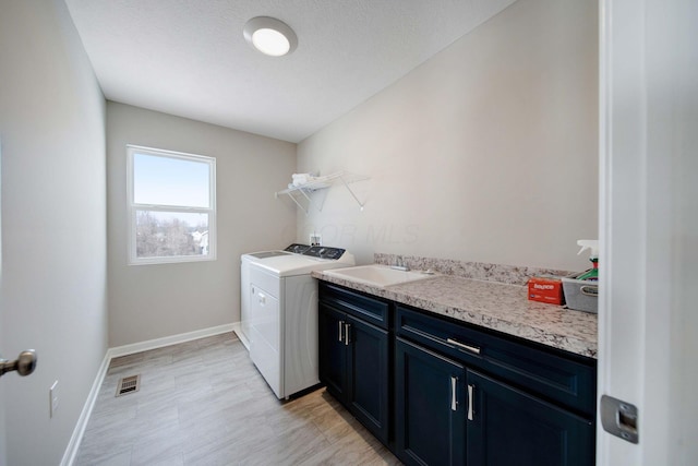 laundry room with cabinets, sink, independent washer and dryer, and a textured ceiling