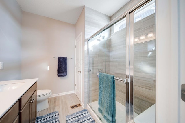 bathroom featuring vanity, toilet, and a shower with shower door