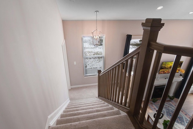 stairway with carpet flooring and a notable chandelier